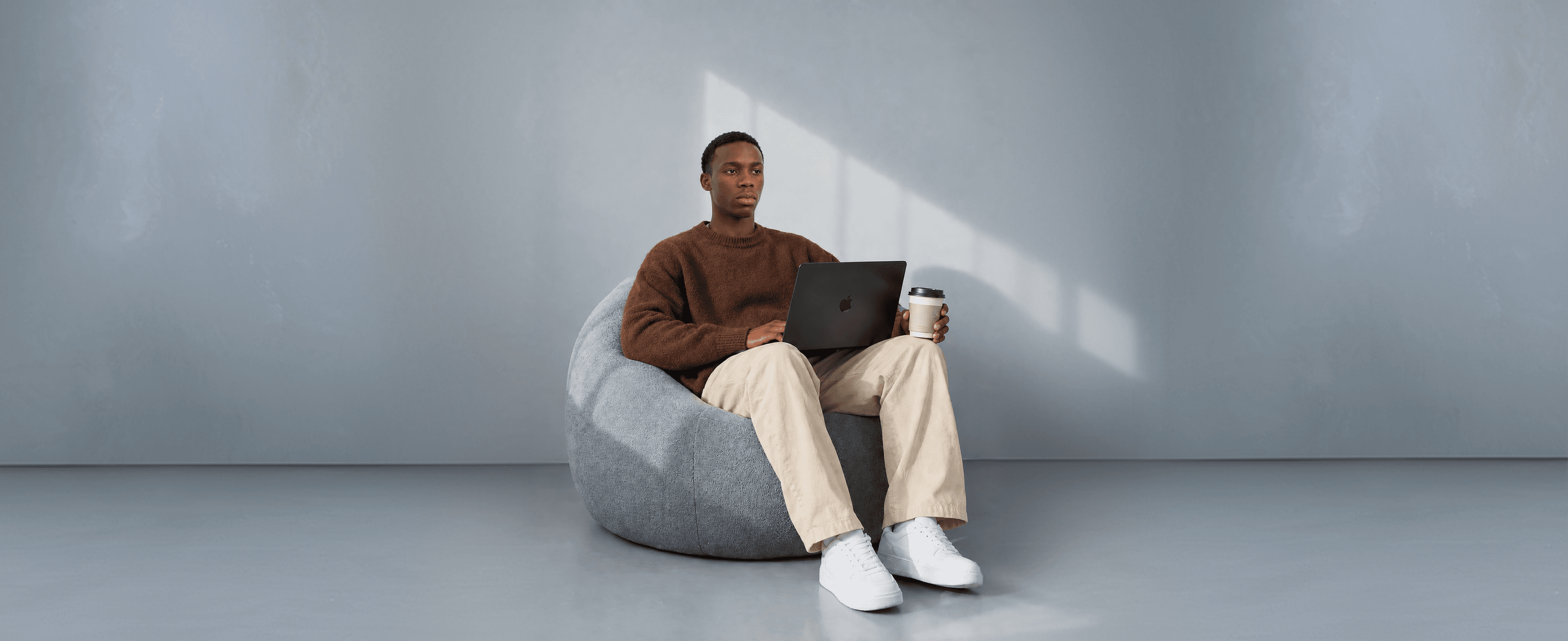 A developer working on a laptop in a studio, coffee in hand